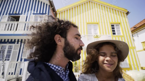 POV Young couple eating ice cream frome one waffle cone. Close-up portrait woman and man enjoing tasty sweets and have fun together on street of Costa Nova, Portugal