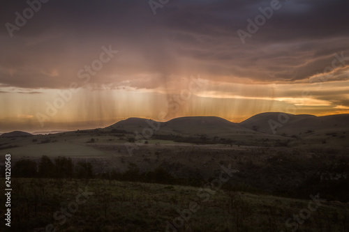 Rain falling on a distant mountain with orange sunset