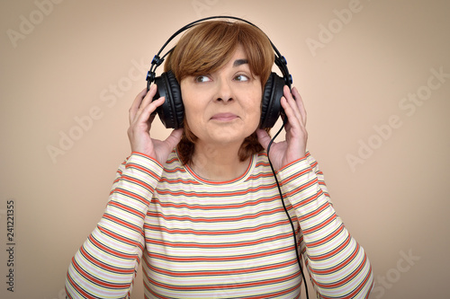 Happy middle aged woman with headphones listening to music and enjoying