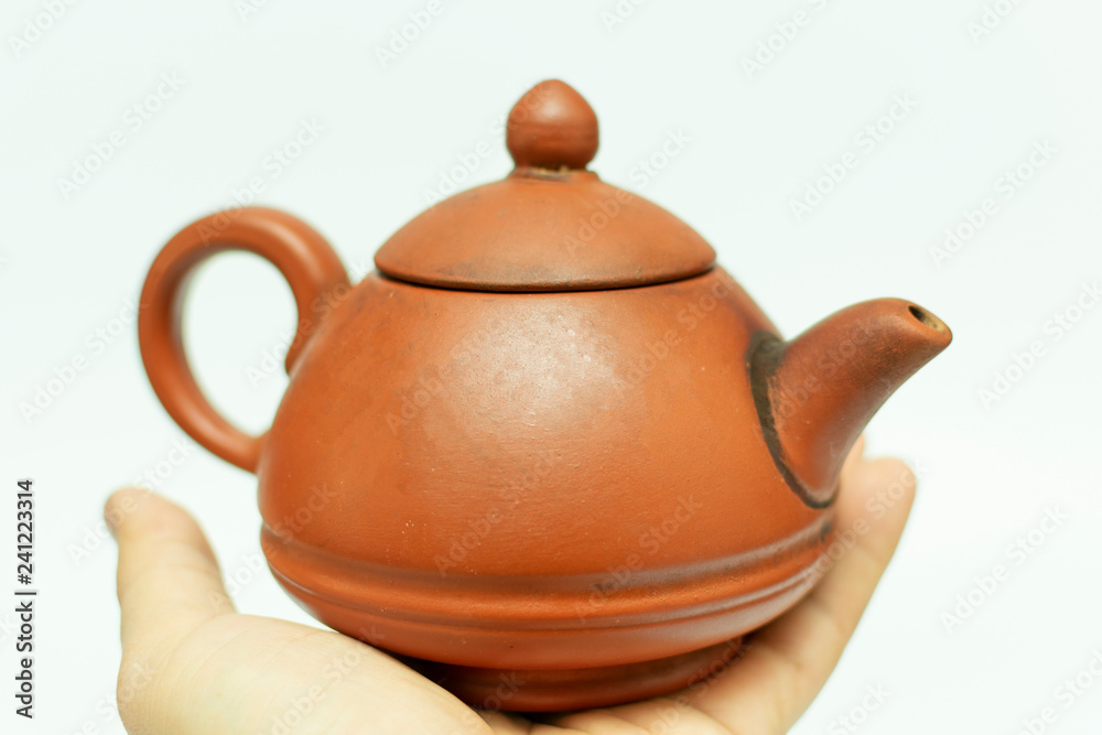 red clay chinese teapot in hand, close-up on white background