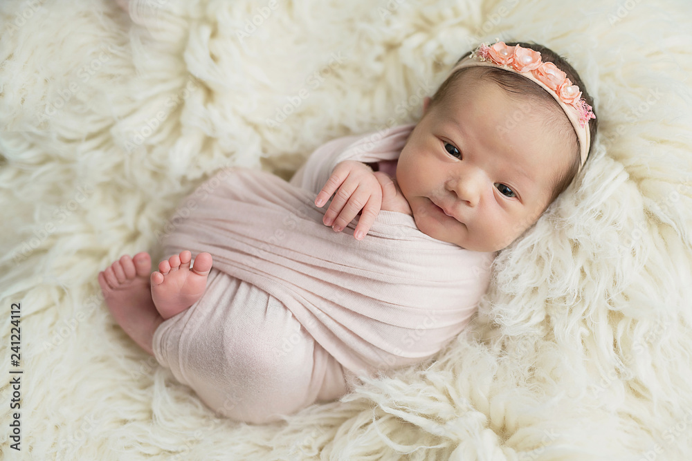 Cute newborn baby girl lies in blanket. Baby goods packaging template. Closeup portrait of newborn baby with smile on face. Healthy and medical concept. Eco conception. Nursery. Cute newborn baby girl lies in blanket. Baby goods packaging template. Closeup portrait of newborn baby with smile on face. Healthy and medical concept. Eco conception. Nursery.
