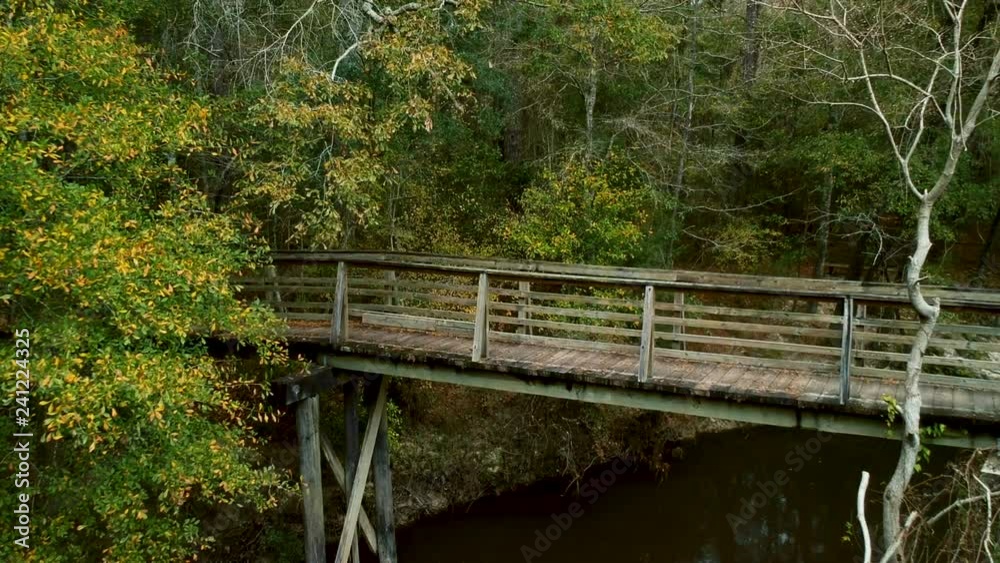 aerial push in establishing shot of an old wooden footbridge in a wooded area aerial push in establishing shot of an old wooden footbridge in a wooded area