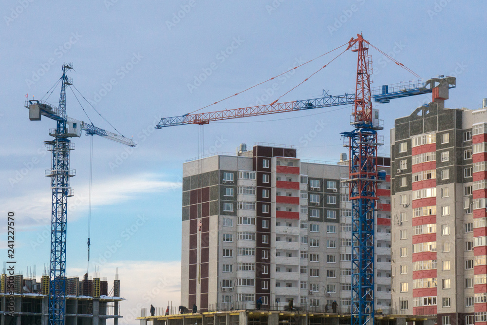 two cranes building a house