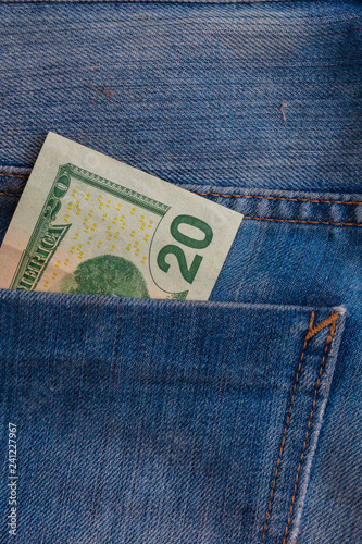 two Dollar banknotes in blue jeans rear pocket closeup