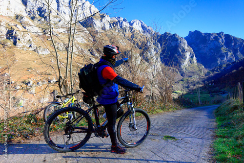 A cyclist with his mountain bike points his hand at the direction of the route