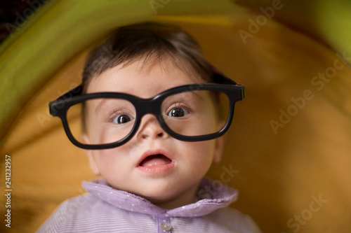 Baby wearing big  glasses, looking at camera