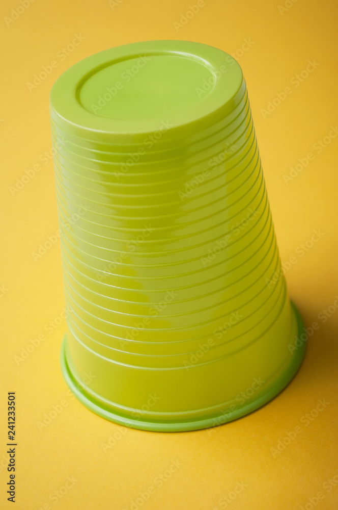 closeup of green plastic cup on yellow background closeup of green plastic cup on yellow background