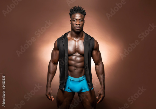 Muscular African American Black athletic fitness model wearing blue  underwear and black hoodie with six pack abs in studio with dramatic  lighting against a brown background Photos | Adobe Stock
