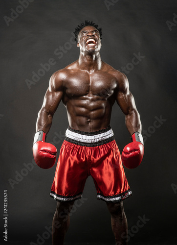 Muscular African American Black male sweaty boxer does an aggressive scream looking up  with dramatic lighting with a black background   © Paul