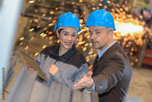 The manager of the factory is showing his female worker how he w