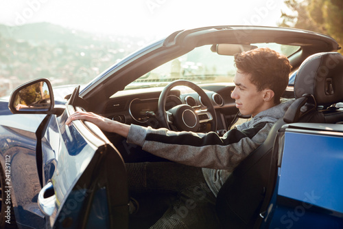 Wallpaper Mural Portrait of sitting boy in luxury sports car opening door at sunrise Torontodigital.ca