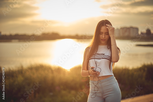 Young beautiful caucasian girl listening to music with smartphone walking in the city with headphones smiling - relax, youth, emancipation concept