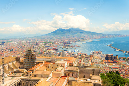 Aerial landscape view on town Naples. Port with ferrie, boats, colorful buildings and Vesuvio volcano with clouds on background. Neapoli hill photo, sunny day Italy, Campania.
