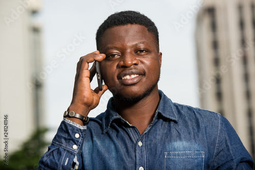 close-up of young african man with mobile phone, happy.