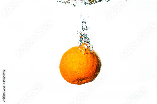 Fresh orange falls into water with white background