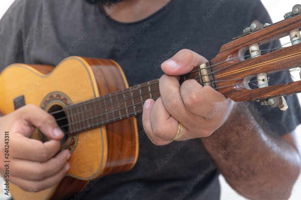 Young man playing ukulele with shirt and black pants. Stock Photo | Adobe  Stock