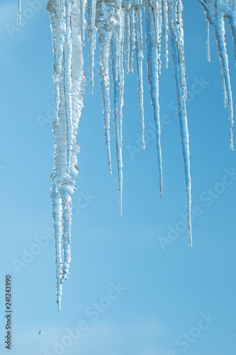 Icicles on the background of a clear sky. ice melts and falls from the roof is a danger to people. water drops. winter and early spring.