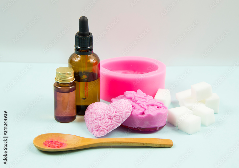 Minimal studio set of different ingredients of making melt and pour handmade soap. White melt and pour soap base pieces, pink silicone mold, coloring, aroma oil, and ready to use pink rose soaps. Minimal studio set of different ingredients of making melt and pour handmade soap. White melt and pour soap base pieces, pink silicone mold, coloring, aroma oil, and ready to use pink rose soaps.