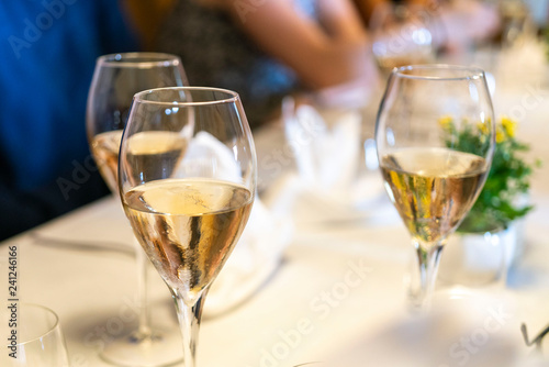 three glasses of white wine on a table with blurry background