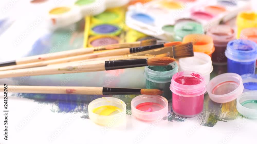 Paint brushes and watercolor paints in motion on the table Paint brushes and watercolor paints in motion on the table