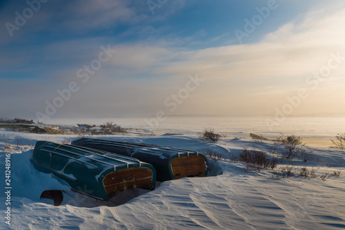 Grounded canoes and small boats on the shore of James Bay in winter, near the northern Cree community of Chisasibi, Quebec.