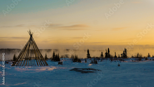 Cree teepee frame at dusk by a misty river in the remote northern boreal forest of Quebec photo
