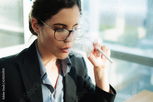 Stressed female executive vaping at work while using laptop Copyspace