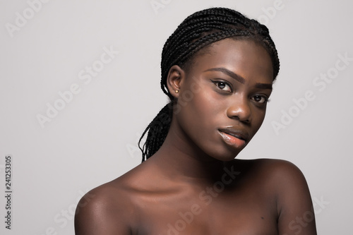 Portrait of young beautiful african woman touching her face isolated over white background. Cleaning face, perfect skin. SPA therapy, skincare, cosmetology, hair removal or plastic surgery concept