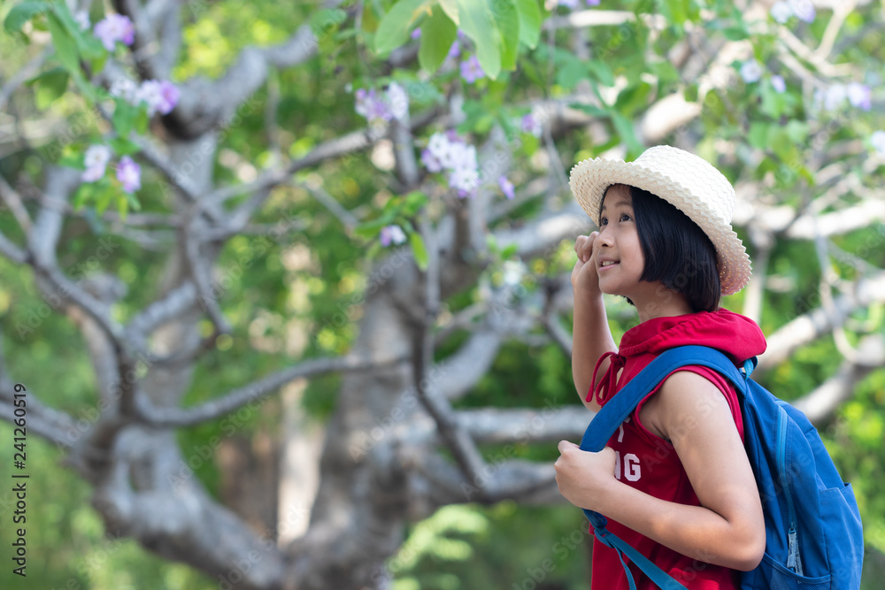 Girls carrying backpacks and looking something in the public park. She is happiness and has the brightest smile and enjoying with nature. Soft focus and blur. Travel concept.