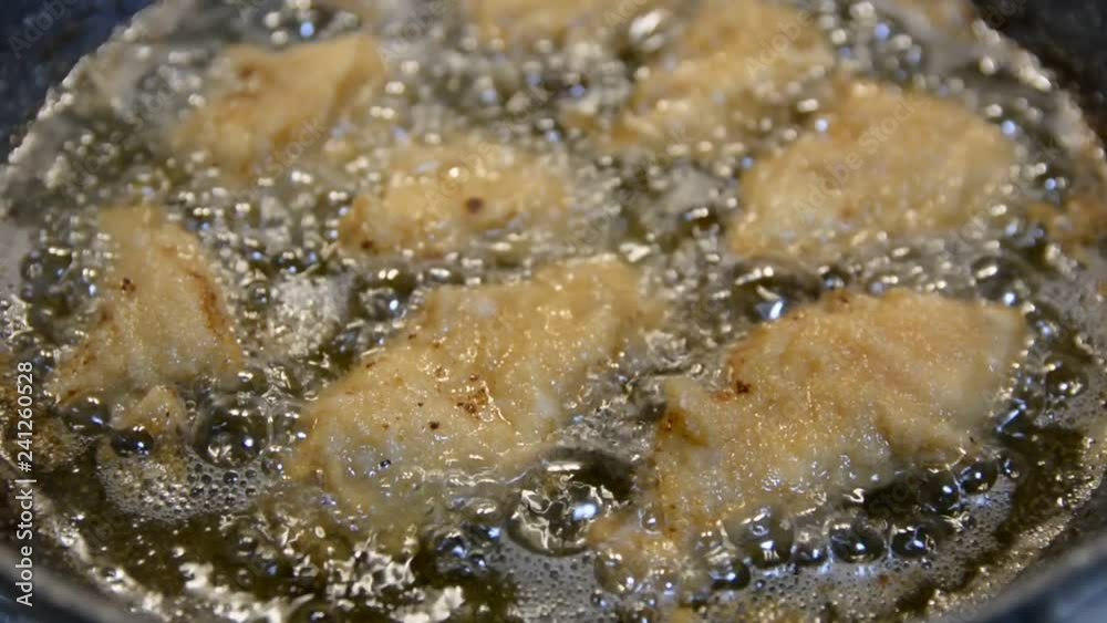 Hot cooking oil in a frying pan with chicken nuggets Hot cooking oil in a frying pan with chicken nuggets