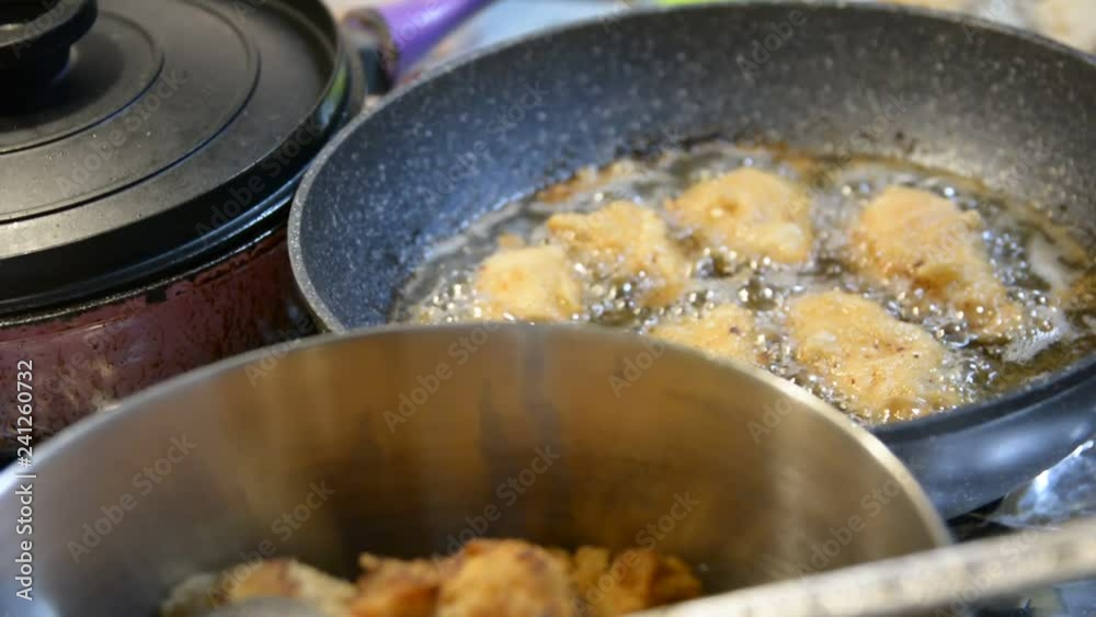 Hot cooking oil in a frying pan with chicken nuggets Hot cooking oil in a frying pan with chicken nuggets