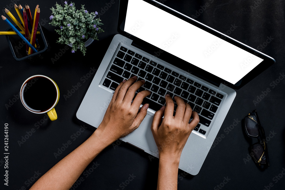 Fototapeta premium Woman hands typing on keyboard in office desk, laptop with blank screen for product display.Top view, Flat lay