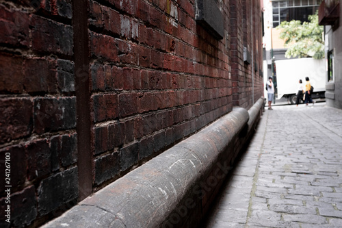 Abstract style photograph looking down a brick lined alley way with cobblestones