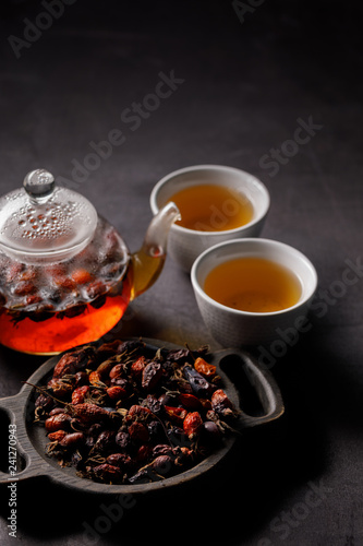 Tea rosehip. Vitamin drink. Teapot and cups with freshly brewed vitamin drink from rosehip, dark mood.