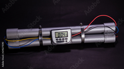 Pipe bomb with an clock timer to trigger detonation on black background