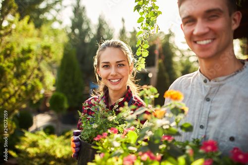 Gardeners happy boy and girl hold pots with plants in beautiful gardens on a warm sunny day