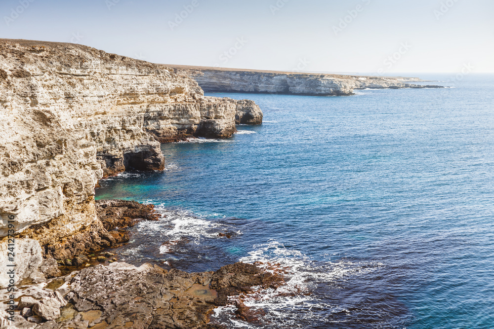 Landscape with shallow blue sea and steep limestone coastline in clear sunny day. Tarkhankut Peninsula, Crimea