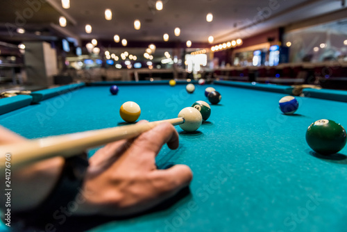 Hand as rack for cue on billiard table with balls
