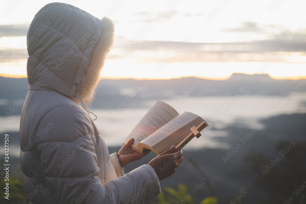 Woman with  cross and bible in hands praying for blessing from god  in the morning, spirituality and religion