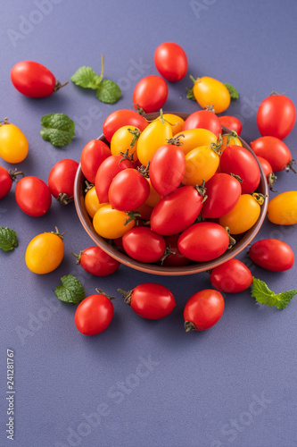 Fresh cherry tomatoes in a wooden bowl isolated on a blue background  close up  copy space