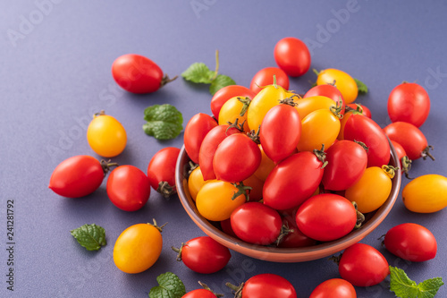 Fresh cherry tomatoes in a wooden bowl isolated on a blue background, close up, copy space photo