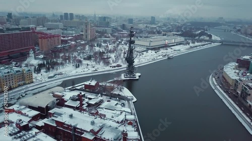Drone flies over the Moscow River to the monument of Peter the Great. All roofs of buildings in the snow. Winter. Overcast weather.