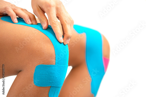 Obraz na plátně Woman applying blue kinesio tape on the injury knee