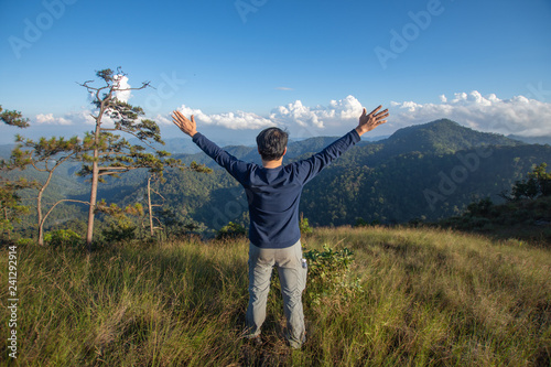 rear of happy man stand on top mountain looking view with mist and cloud at Doi Langka Luang, Chiang Rai province. soft focus.