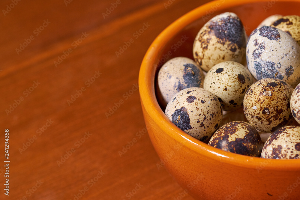 Quail eggs in clay bowl on brown wooden background. Selective focus Quail eggs in clay bowl on brown wooden background. Selective focus