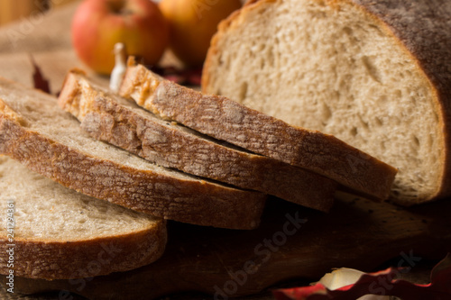  Pokorojony świeży chleb w kompozycji z jesiennymi liśćmi i czosnkiem.