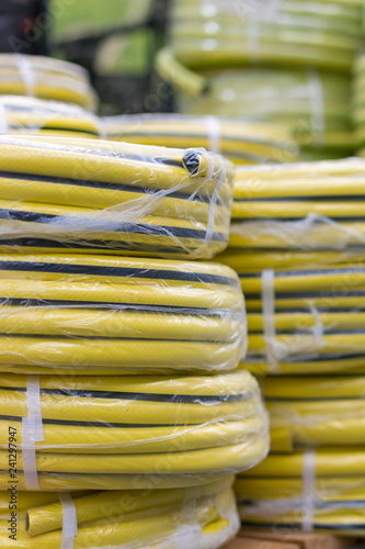 stacks of rolls yellow pvc plastic pipe on the counter in the store. Sale Hoses in the garden of various manufacturers, on shelves in store. Hose for watering in the store.