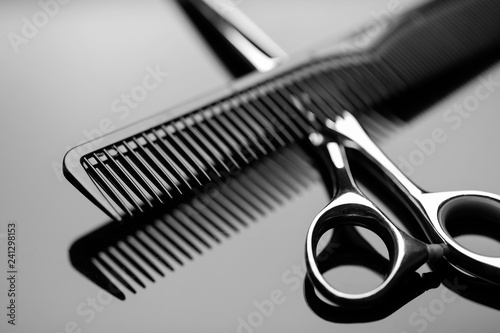 фотографія Barber scissors and a hairbrush closeup on the mirror surface of the table
