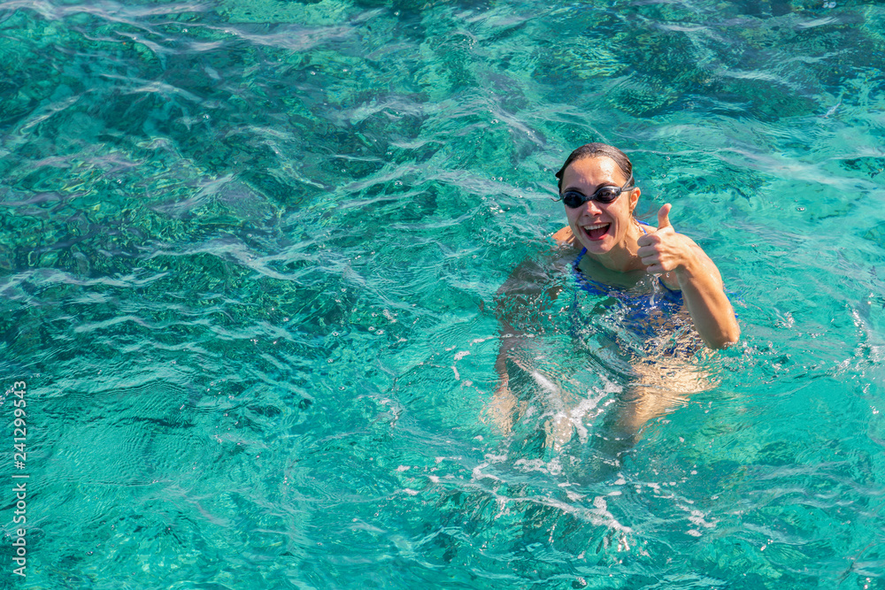 Happy young woman in a blue swimsuit in the sea on vacation. copy space