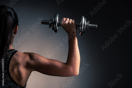 Fototapeta Naklejka Na Ścianę i Meble -  Beautiful young woman workout with dumbbell over gray background in fitness gym club